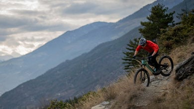 Mountainbiker fährt einen felsigen Trail hinunter mit einer malerischen Bergsicht