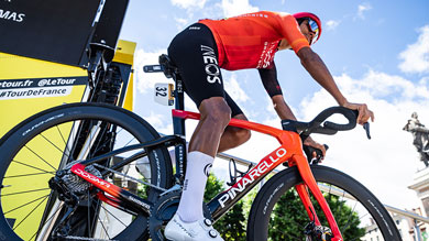 Un ciclista in maglia rossa corre su una Pinarello durante una gara