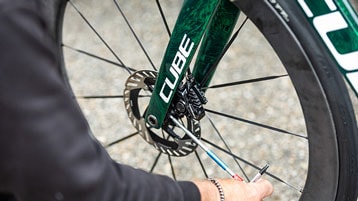 Person working on the disc brake of a green Cube bicycle