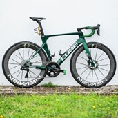 Green Cube road bike with Newmen wheels parked against a white wall