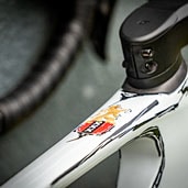 Close-up of bicycle frame with logo and handlebars in the background