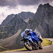 Motorcyclist riding through mountainous landscape with a spare tire mounted on the bike