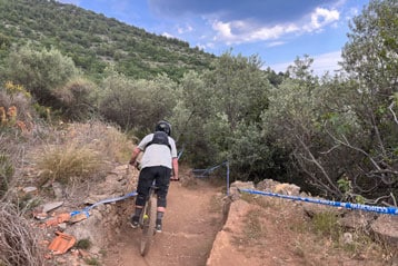 Mountainbiker auf einem Schotterweg, umgeben von Bäumen.