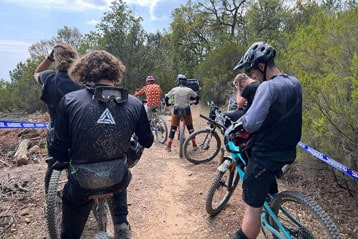 Person mit Mountainbike neben dem Meer auf einem felsigen Weg.