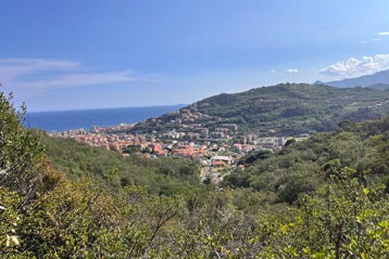 Malerische Aussicht auf eine Küstenstadt mit Hügeln und Meer im Hintergrund.