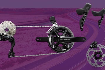 Shimano-105-Radkomponenten vor violettem Hintergrund.
