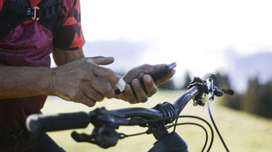 Personne utilisant un smartphone à côté d'un vélo dans un cadre pittoresque.