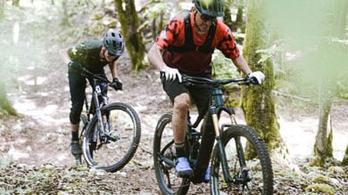 Deux vététistes sur un sentier forestier.