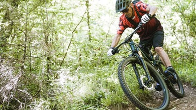 Cycliste portant un casque roulant en VTT sur un sentier forestier.