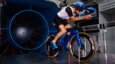 Ein Mann testet die Aerodynamik des Fahrrads in einer Indoor-Umgebung.