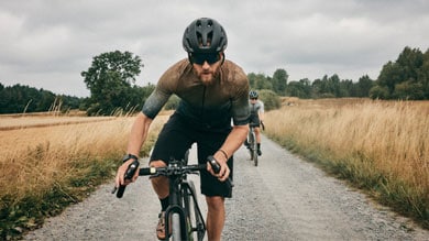 Two cyclists riding on a gravel path through a rural landscape