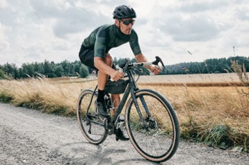 Cyclist riding a bike on a gravel road in a rural area