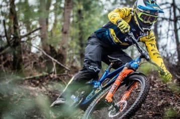 Mountain biker racing through a forest trail wearing protective gear