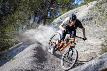 Mountain biker riding on rocky terrain, kicking up dust