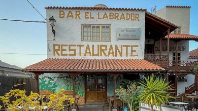 Buitenkant van Bar El Labrador Restaurante met terraszitplaatsen en planten.