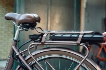 Person removing battery from electric bike mounted on the rear rack