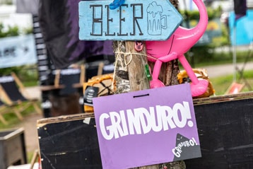 Signs on a tree for Stage, Beer, and Grinduro! with a pink flamingo decoration