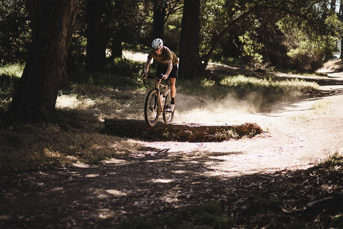 Man jumping over a log in the middle of the trail on his Shimano GRX equipped gravel bike